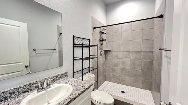 a bathroom with a granite countertop sink toilet and shower