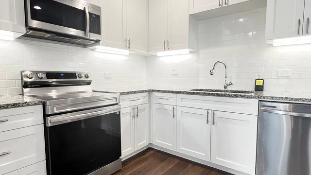 a kitchen with cabinets stainless steel appliances and wooden floor