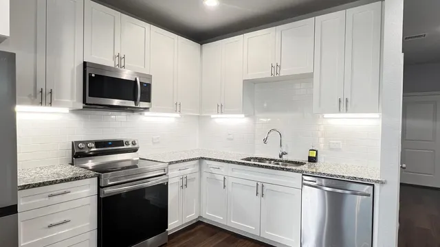 a kitchen with stainless steel appliances granite countertop a sink stove and microwave