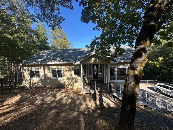 a front view of a house with yard tree and outdoor seating