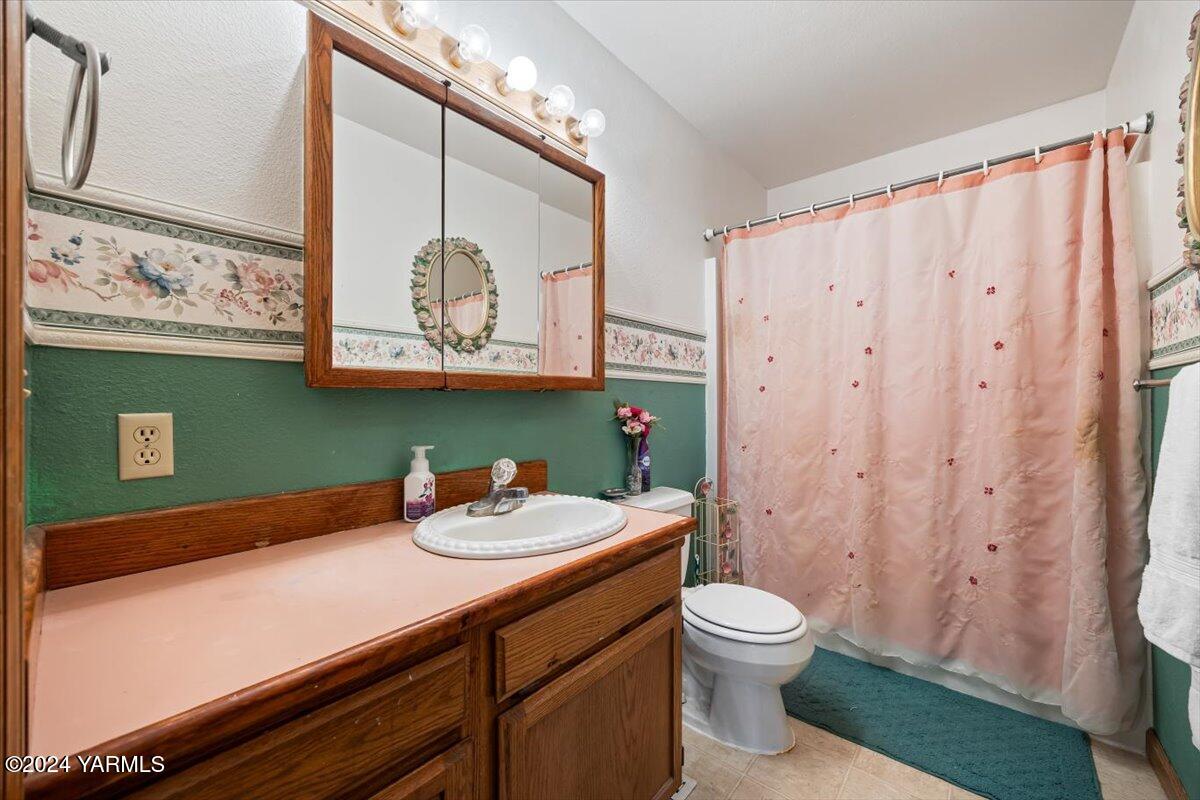 1802 Young Street Grandview, WA 98930 - Photo 28 of 31 a bathroom with a sink a toilet and shower curtain