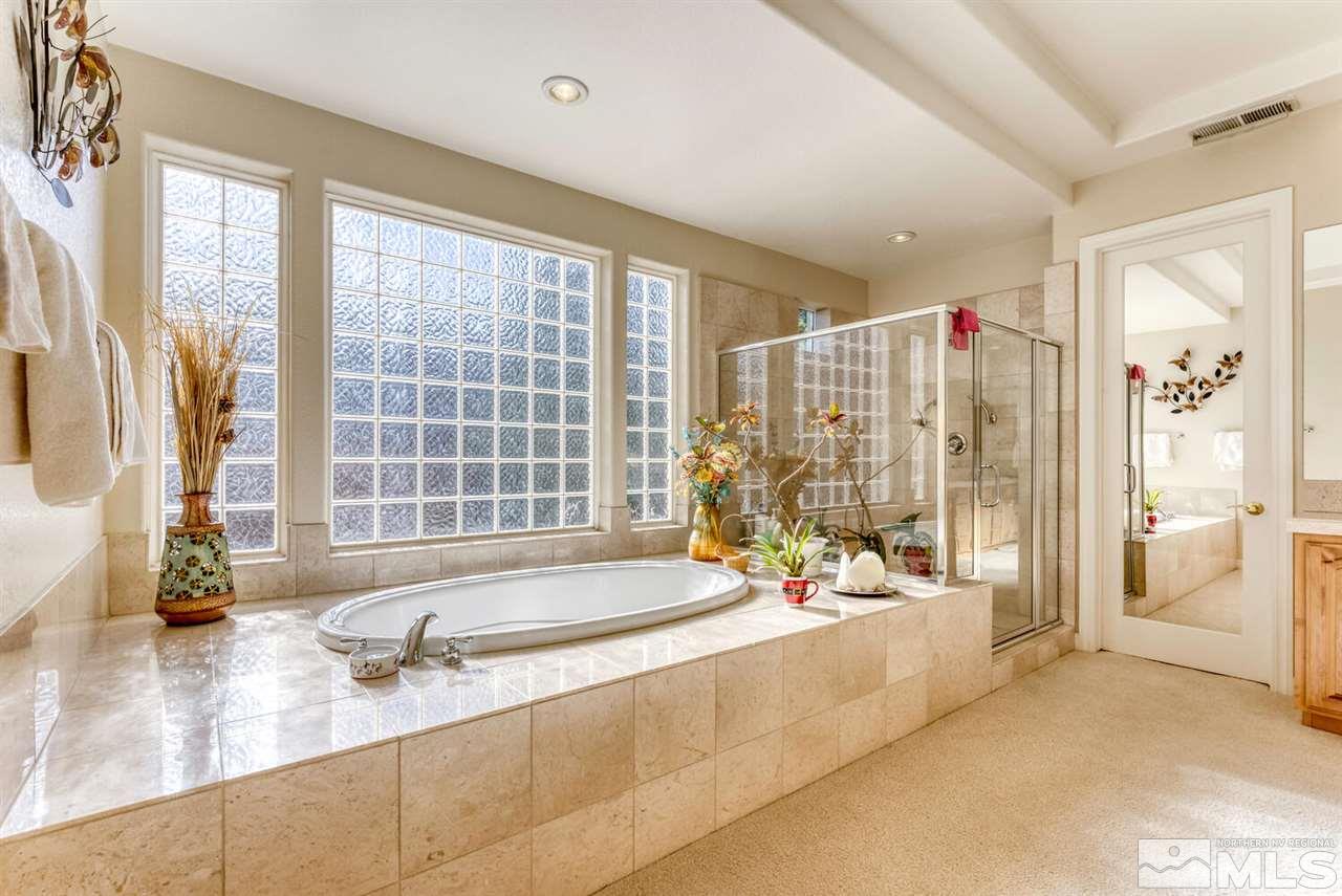 10040 Burghley Lane Reno, NV 89521 - Photo 26 of 39 a bathroom with a tub a sink and a large mirror next to a window