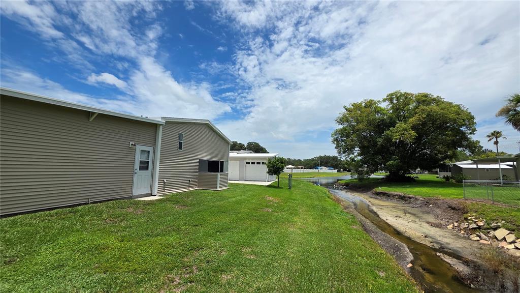36740 Strand Drive Zephyrhills, FL 33542 - Photo 5 of 74 a view of a house with a big yard potted plants and large tree