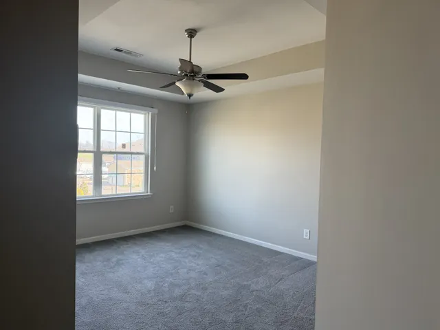 an empty room with windows and fan