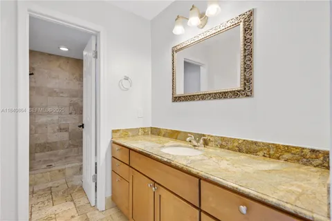 a bathroom with a granite countertop sink a mirror and shower