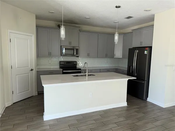 a view of kitchen with stainless steel appliances wooden floor and window