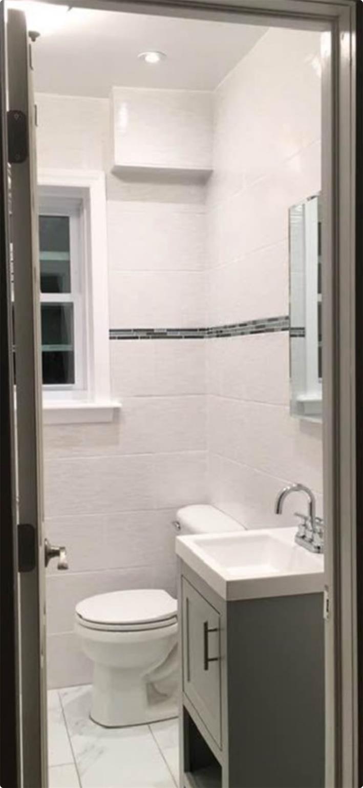 218-34 104th Avenue Queens, NY 11429 - Photo 24 of 27 Bathroom featuring vanity, tile walls, and toilet