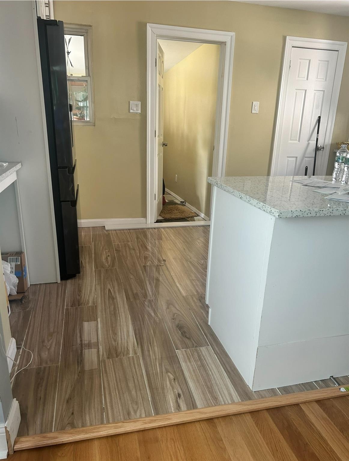 218-34 104th Avenue Queens, NY 11429 - Photo 6 of 27 Kitchen with white cabinetry, light stone countertops, black fridge, and hardwood / wood-style floors