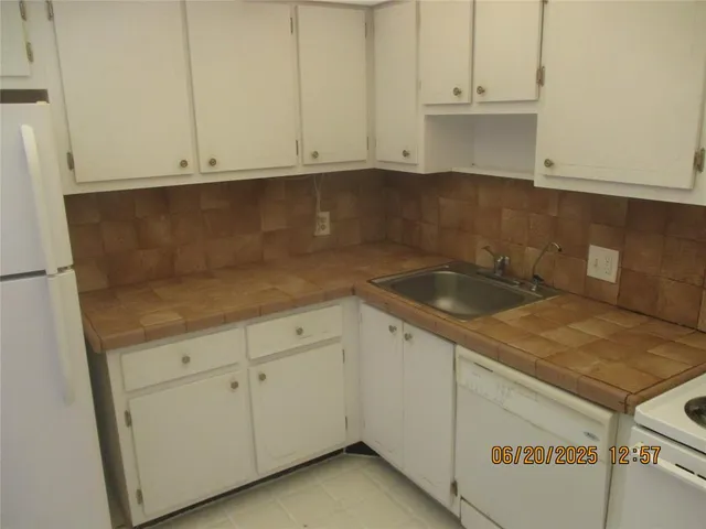 a kitchen with granite countertop white cabinets and a sink
