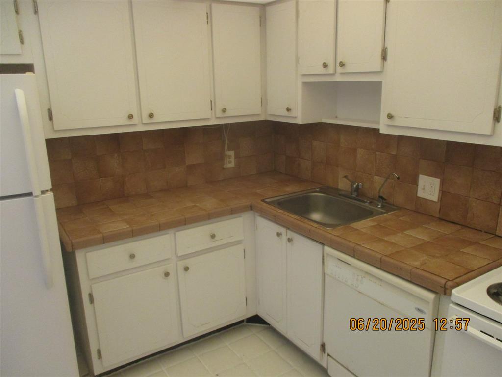 2651 South Course Drive, Unit 404 Pompano Beach, FL 33069 - Photo 7 of 40 a kitchen with granite countertop white cabinets and a sink