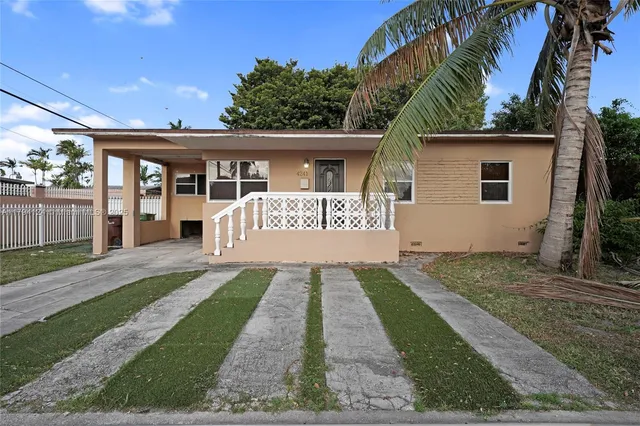 a front view of a house with a yard and potted plants