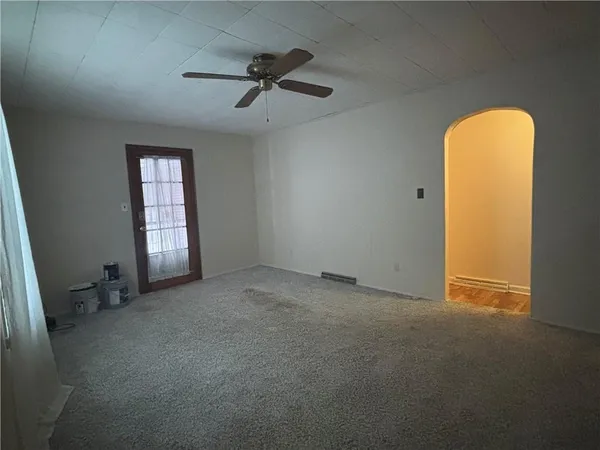 an empty room with windows and fan