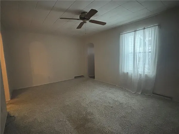 an empty room with ceiling fan and windows