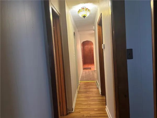 a view of a hallway with wooden floor and a mirror