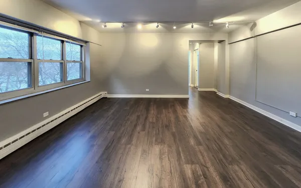 an empty room with wooden floor and windows