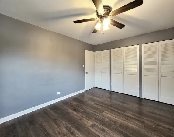 an empty room with wooden floor and fan