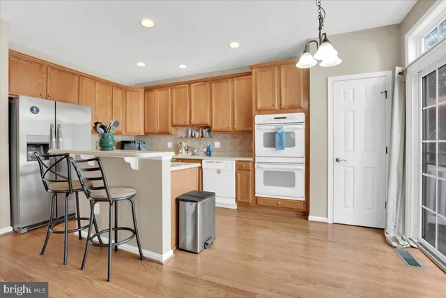 a kitchen with stainless steel appliances granite countertop a refrigerator oven a sink dishwasher and white cabinets with wooden floor