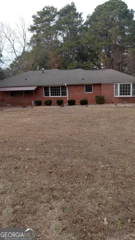 a front view of house with yard and trees in the background