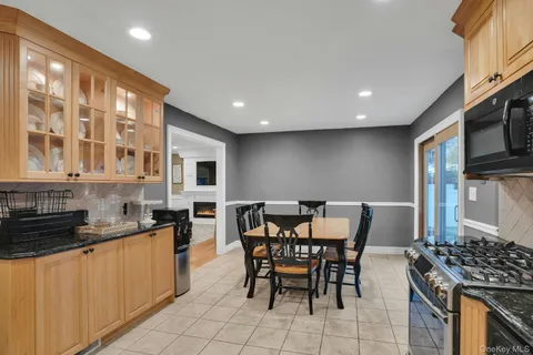 a kitchen with stainless steel appliances granite countertop a stove a sink a microwave a dining table and chairs