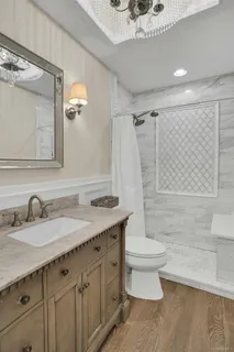 a bathroom with a granite countertop sink a toilet a mirror and shower
