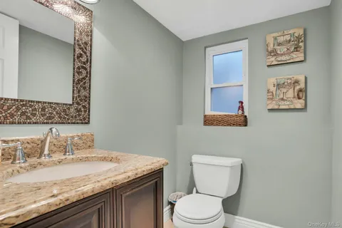 a bathroom with a granite countertop toilet sink and mirror