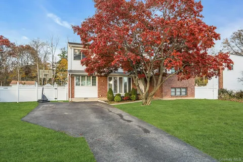 a front view of a house with a garden and tree