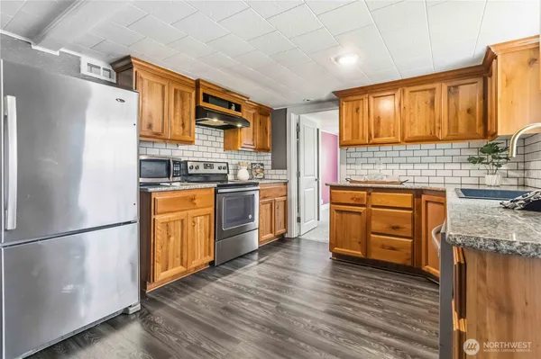 a kitchen with stainless steel appliances granite countertop a stove a sink dishwasher and a refrigerator with wooden floor