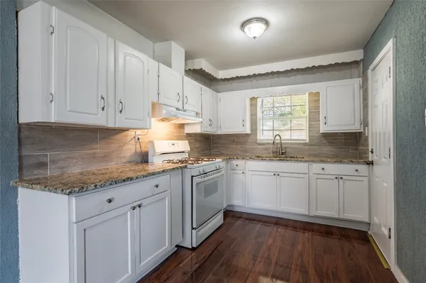 a kitchen with granite countertop cabinets stainless steel appliances a sink and a window