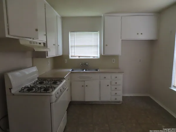 a kitchen with granite countertop a sink a stove and cabinets