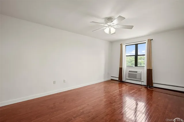 an empty room with wooden floor chandelier fan and windows