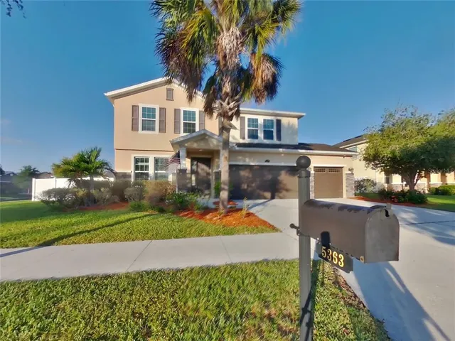 a front view of a house with a yard and potted plants