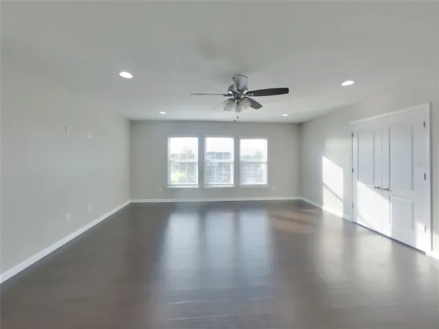 a view of an empty room with a window and wooden floor