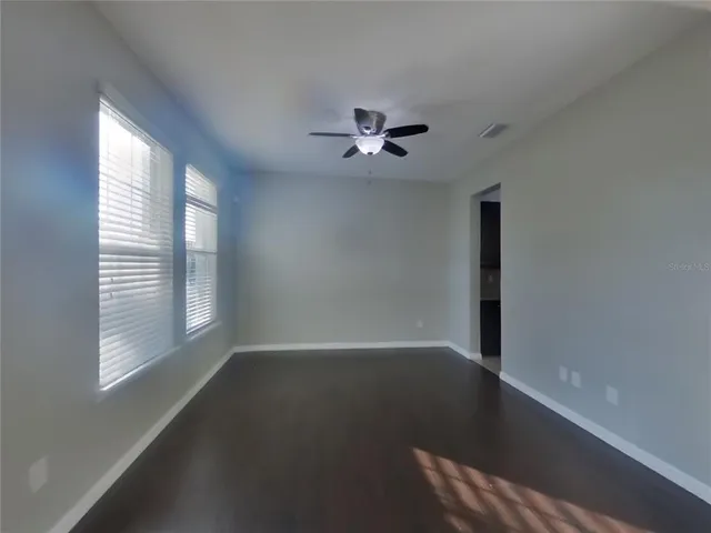 an empty room with windows and fan
