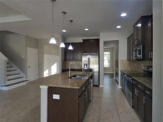 a kitchen with stainless steel appliances granite countertop a sink a stove top oven a counter space and cabinets