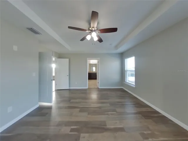 a view of an empty room and window and chandelier fan