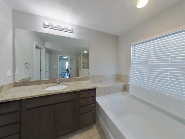 a bathroom with a granite countertop sink a toilet a large mirror and bathtub