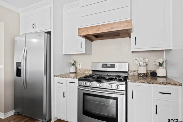 a kitchen with stainless steel appliances granite countertop a refrigerator a stove and white cabinets