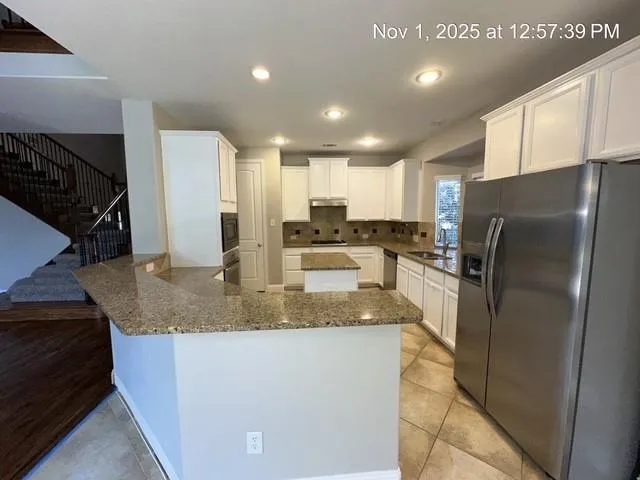 a kitchen with stainless steel appliances granite countertop a refrigerator a stove and a sink