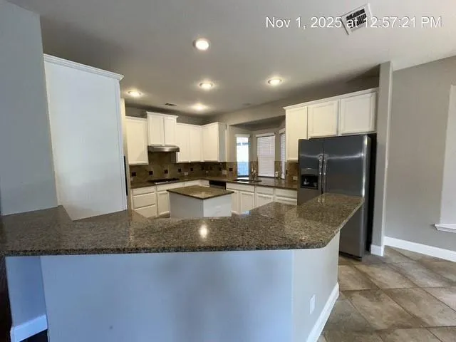 a kitchen with stainless steel appliances granite countertop a sink a refrigerator and a granite counter tops