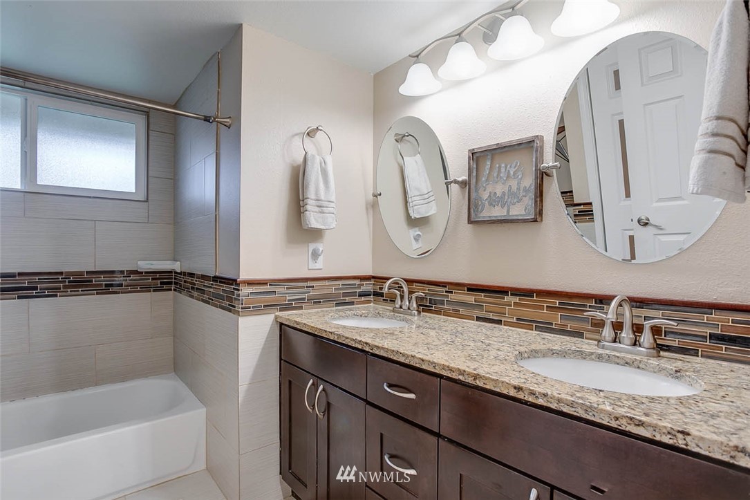 16120 Southeast 145th Place Renton, WA 98059 - Photo 14 of 22 a bathroom with a granite countertop sink a mirror a vanity and bathtub