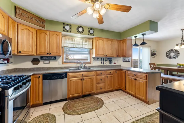 a kitchen with stainless steel appliances granite countertop a sink a stove a refrigerator cabinets and dining table