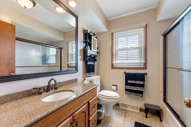 a bathroom with a granite countertop toilet sink double vanity and mirror