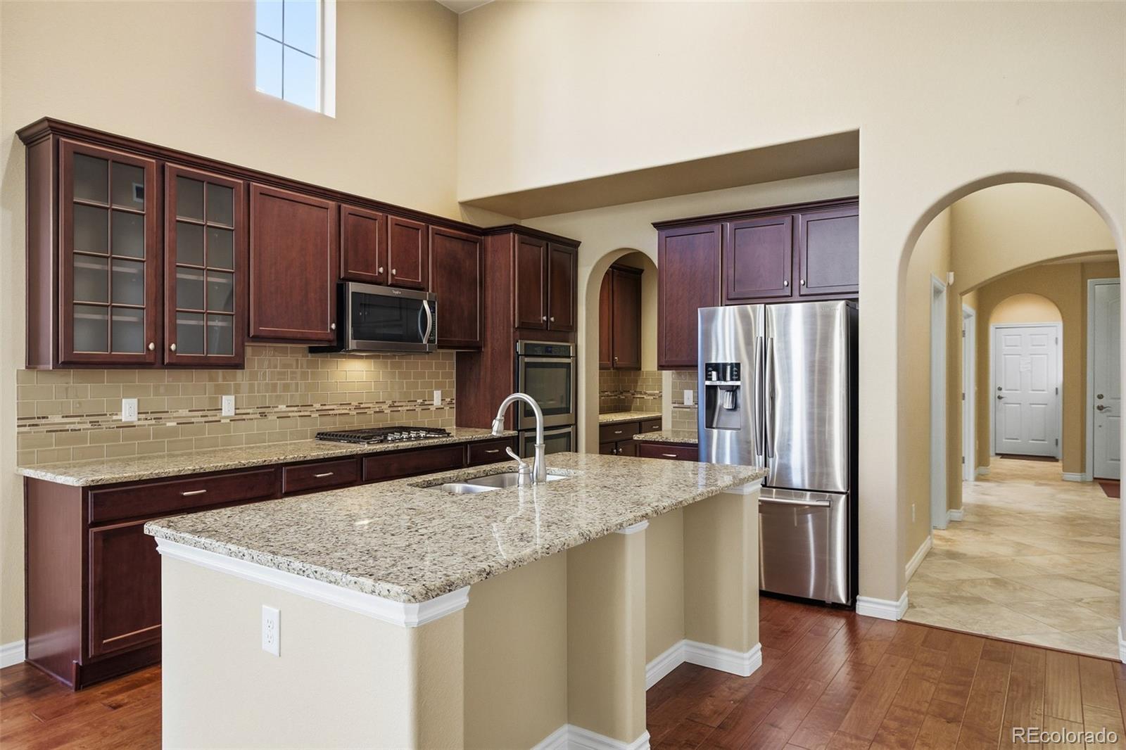 9470 Sori Lane Highlands Ranch, CO 80126 - Photo 9 of 32 a kitchen with stainless steel appliances granite countertop a refrigerator a sink and wooden cabinets