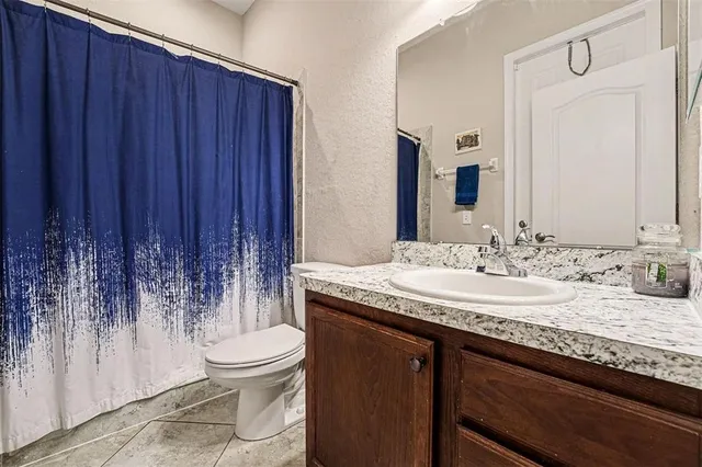 a bathroom with a granite countertop sink a toilet and a mirror