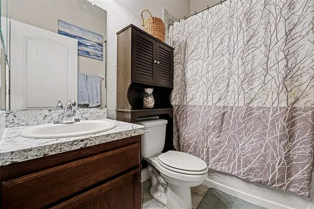 a bathroom with a granite countertop toilet sink and mirror