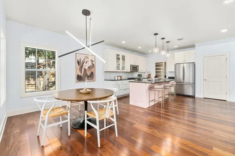 a view of a dining room and livingroom with furniture wooden floor a chandelier