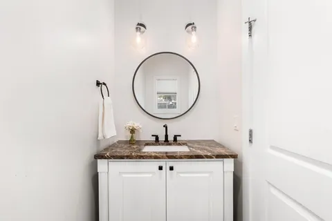 a bathroom with a granite countertop sink and a mirror