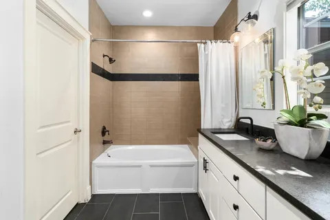 a bathroom with a tub shower sink and vanity