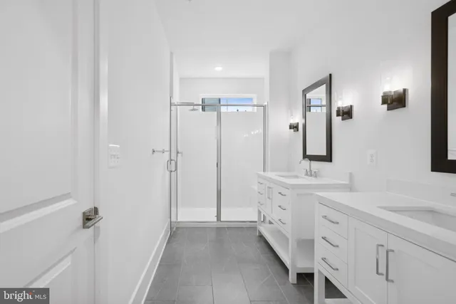 a spacious bathroom with a double vanity sink a mirror and shower