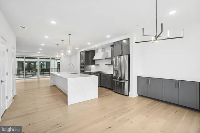 a large kitchen with stainless steel appliances kitchen island a large counter top and a refrigerator